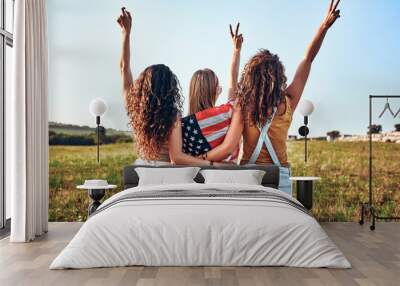 Three happy young women with national american flag on a field Wall mural