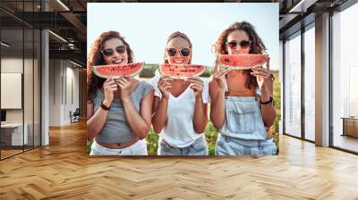 Three nice girls having fun eating watermelon In the park. Wall mural