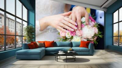 Hands of bride and groom on wedding bouquet. Marriage concept Wall mural