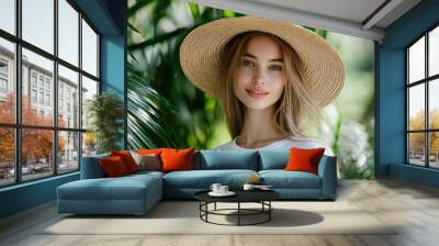 Smiling woman in a straw hat with green foliage background in a tropical setting Wall mural