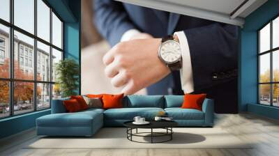 The groom in dark suit puts on a watch, closeup Wall mural