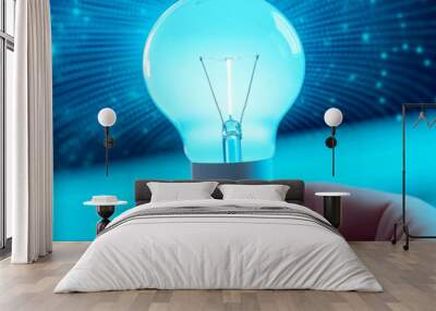 A glowing light bulb held in a hand, symbolizing innovation and ideas in a digital environment with a blurred background. Wall mural