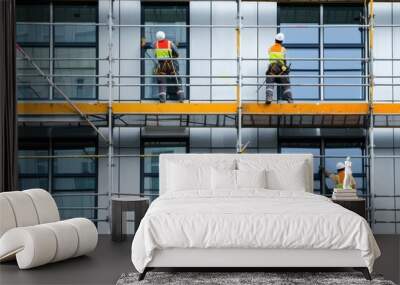 Construction workers in safety gear working on scaffolding at a high-rise building site, ensuring structural integrity and window installation. Wall mural