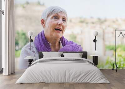 older woman with purple scarf on her neck and White hair smiling Wall mural