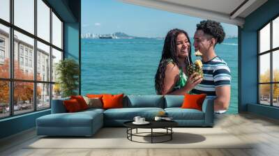 Romantic moments of happy Latin couple enjoying a tropical vacation at the beach. Cuddling and having fun together. Wall mural