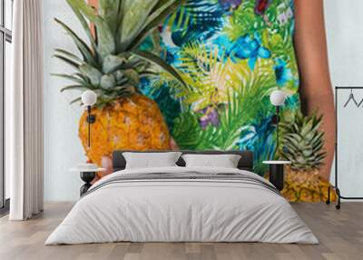 View of an incognito woman holding a fresh and tasty pineapple in her hands against a white background. Wall mural