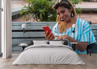 Young woman using cellphone in the park Wall mural