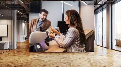 a female worker in an exchange office counts money using counting machine. Wall mural