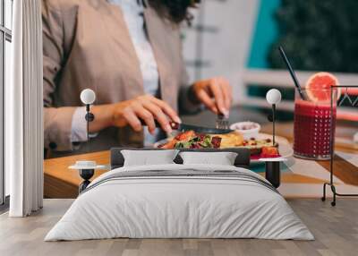 A middle-aged businesswoman enjoys a healthy meal and fresh beetroot and grapefruit juice at the organic food restaurant. Wall mural