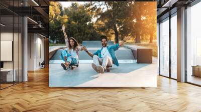 Beautiful young couple enjoying outdoors in city skateboarding park Wall mural