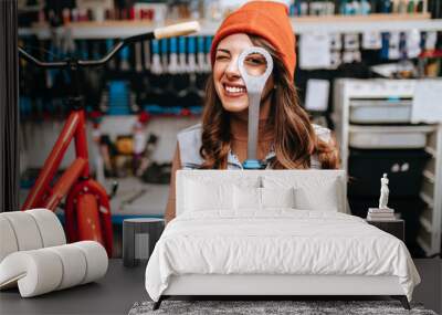 Beautiful young female mechanic having fun and enjoying while repairing bicycles in a workshop.. Wall mural