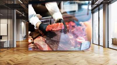 Closeup on butcher's hands in gloves working in butchery. Wall mural