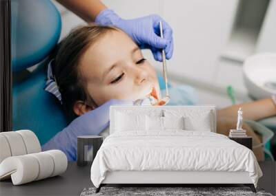 Cute little girl sitting on dental chair and having dental treatment. Wall mural