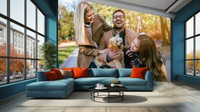 Disabled father in wheelchair enjoying with his daughter, wife and dog outdoors in park. Wall mural