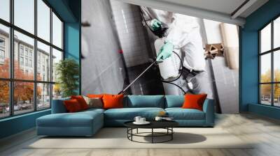 Exterminator in work wear spraying pesticide with sprayer. Wall mural