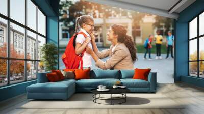 First day at school. Mother leads a little child school girl in first grade. Wall mural