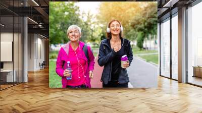 Happy mother and daughter jogging together outdoors in park. Wall mural