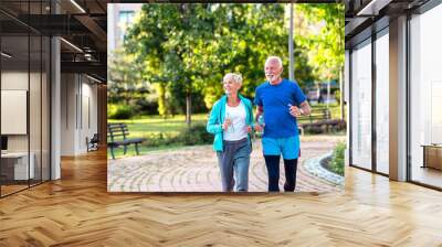 Happy senior couple jogging outdoors in park. Wall mural