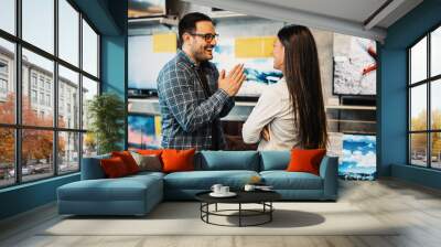 Happy young couple buying TV in store. Wall mural