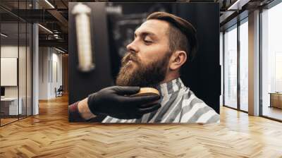 Hipster young good looking man visiting barber shop. Trendy and stylish beard styling and cut. Wall mural