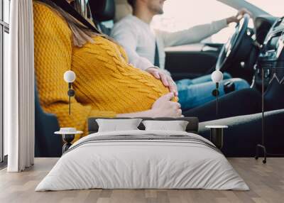 Husband and his pregnant wife driving in car. Wall mural