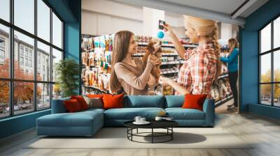 Mother and daughter with their poodle puppy in pet shop. Wall mural