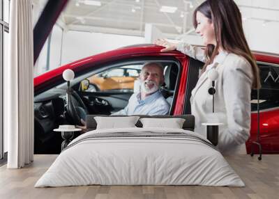 Saleswoman at the dealership showroom talking with a customer. Wall mural