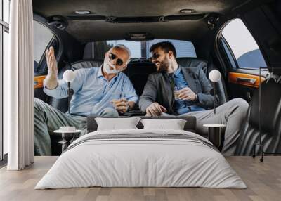 Senior businessman and his assistant sitting in limousine and celebrating their job success. Wall mural