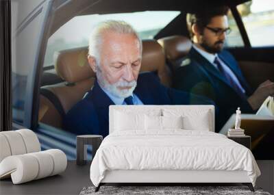 Senior businessman and his assistant sitting in limousine and working Wall mural