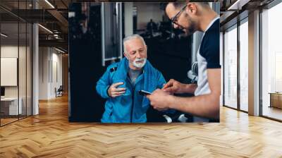 Senior man exercising in gym with his personal trainer. Wall mural