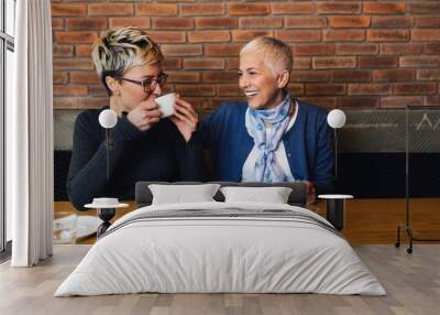 Senior mother sitting in cafe bar or restauant with her middle age daughter and enjoying in conversation. Wall mural