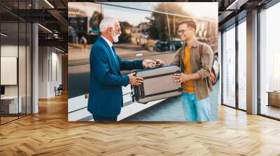 The senior bus driver accepts luggage from passenger. Wall mural