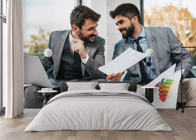 Two cheerful businessmen working together in office. Wall mural