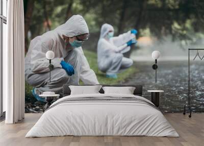 Two scientists in protective suits taking water samples from the river. Wall mural