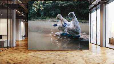 Two scientists in protective suits taking water samples from the river Wall mural