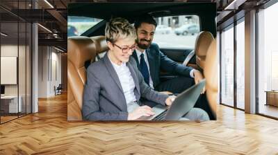 young business woman and her assistant sitting in limousine talking and working. Wall mural