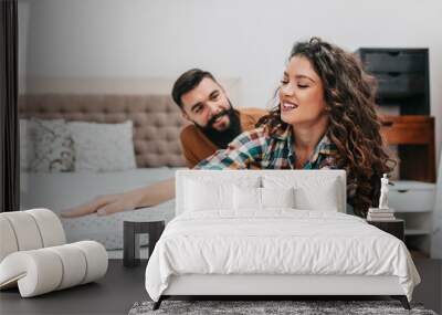 Young couple buying new bed and mattress in big furniture store Wall mural