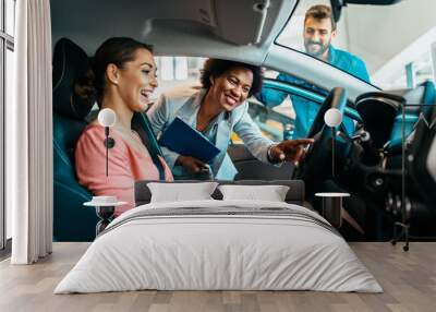 Young couple talking with saleswoman at car showroom about new car they want to buy. Wall mural