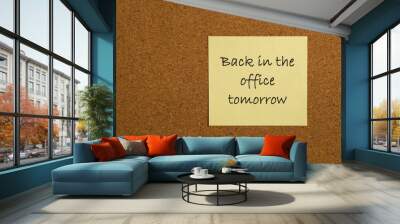 Small yellow sticky note on an office cork bulletin board with the message back in the office tomorrow Wall mural