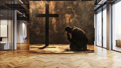 Silhouette of a man praying on his knees in front of a cross with a smoky background. Concept of faith, prayer, and reflection. Wall mural