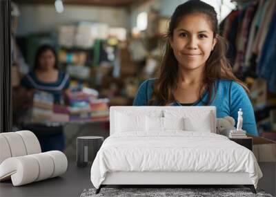 cheerful young woman is holding a box of donated items in a thrift store setting, with another person visible in the background. Wall mural