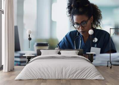 Doctor or a nurse, wearing scrubs and a stethoscope, working at a desk with a laptop and medical textbooks. Wall mural