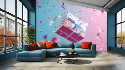 Pink gift box with blue ribbon on blue and pink background with colorful confetti flying around. Festive background. Birthday celebration concept Wall mural