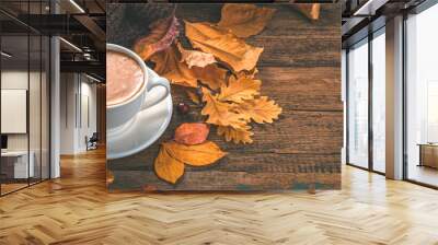 Cappuccino and autumn foliage on a wooden background. Cozy autumn composition. Side view, copy space Wall mural