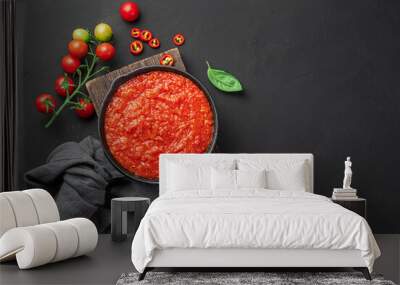 Tomato sauce in a frying pan on a wooden board on a black background. Marinara sauce with basil. Top view, copy space. Wall mural