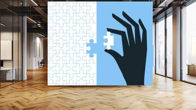 A dark hand places a white puzzle piece on a blue background Wall mural