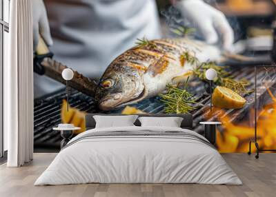 Chef grills whole fish with herbs and lemons on flaming barbecue Wall mural