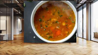 A bowl of steaming hot vegetable soup with fresh parsley garnish. Wall mural