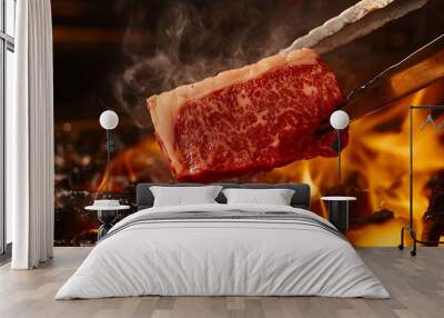 A piece of raw red meat being held by tongs over a hot fire. Wall mural