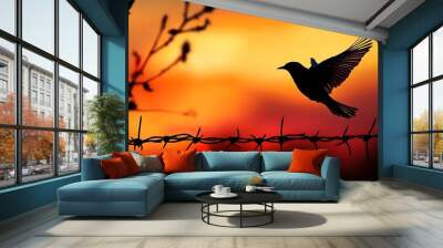 A single bird takes flight against a setting sun and barbed wire fence, symbolizing freedom and hope. Wall mural